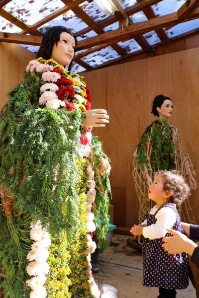 着せ替え中の菊人形を見上げる子ども